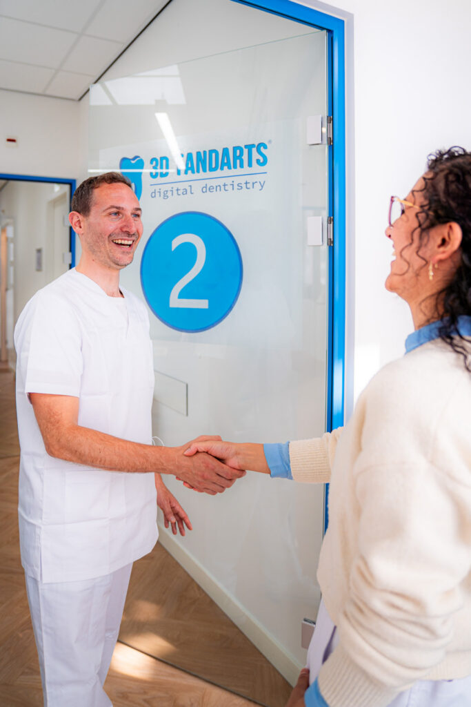 Dentista che stringe la mano a una paziente all'ingresso di 3D Tandarts Schiedam