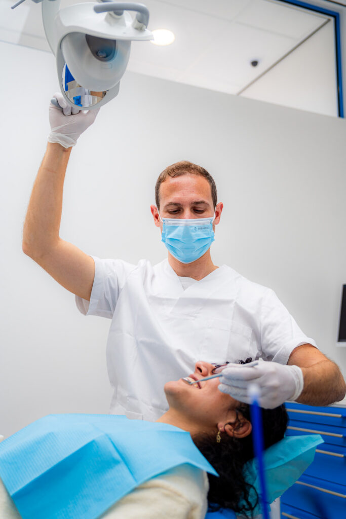 Dentista con mascherina che orienta la lampada operatoria presso 3D Tandarts Schiedam